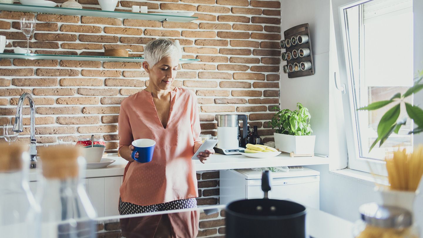 woman in kitchen with tea and phone