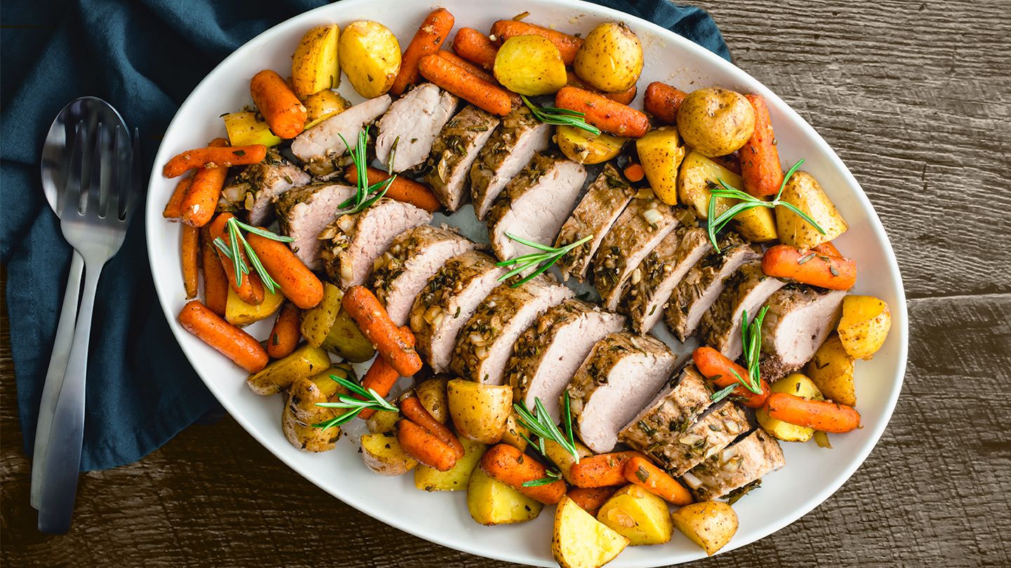 pork tenderloin on a plate surrounded by roasted vegetables