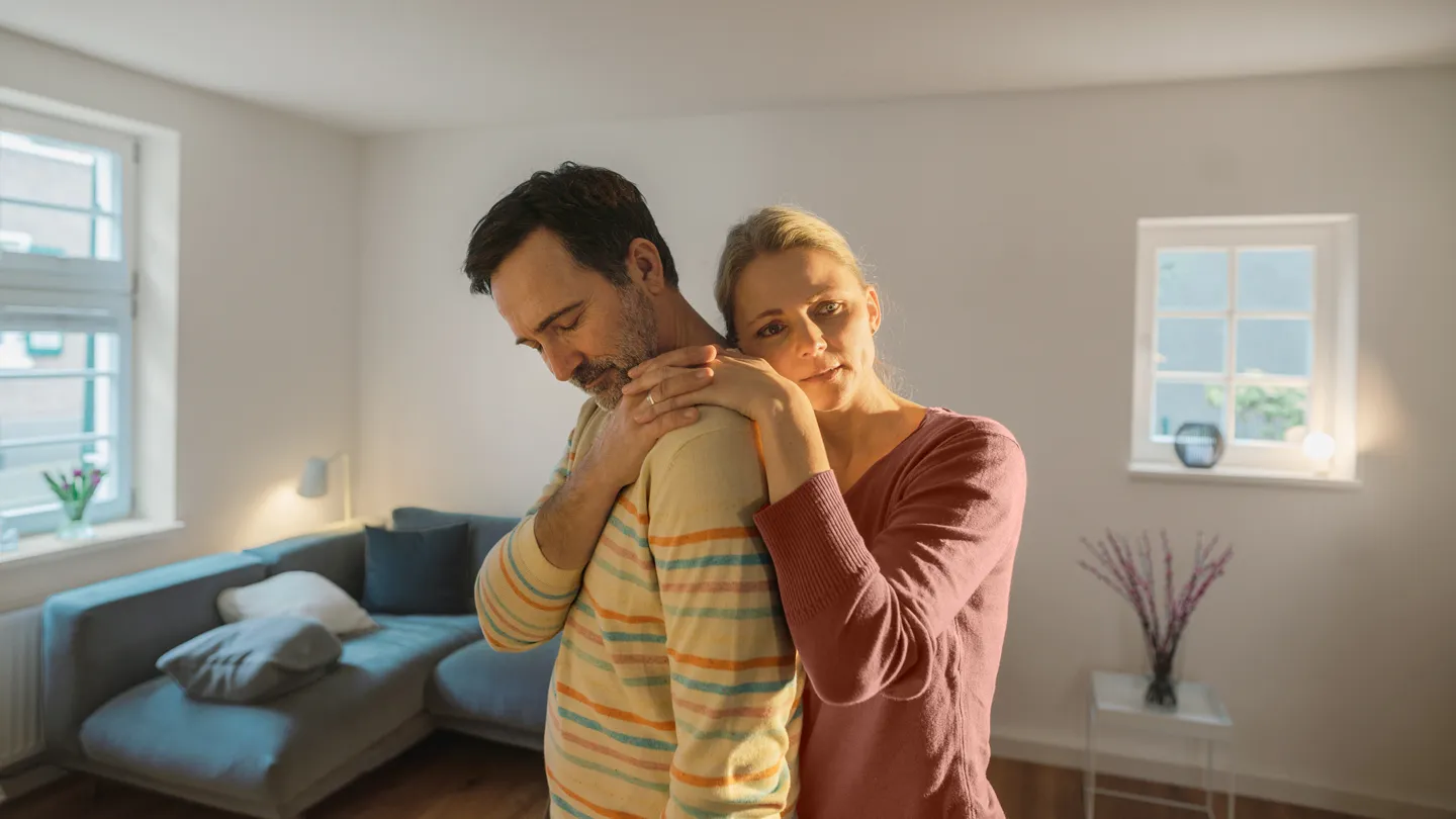 Contemplative mature couple standing in living room at home
