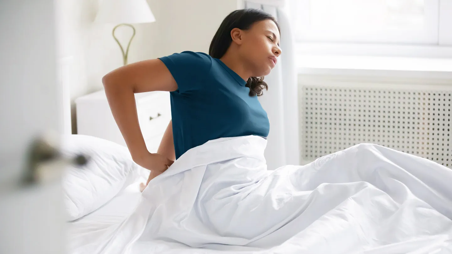 woman waking up tired in bed cramps