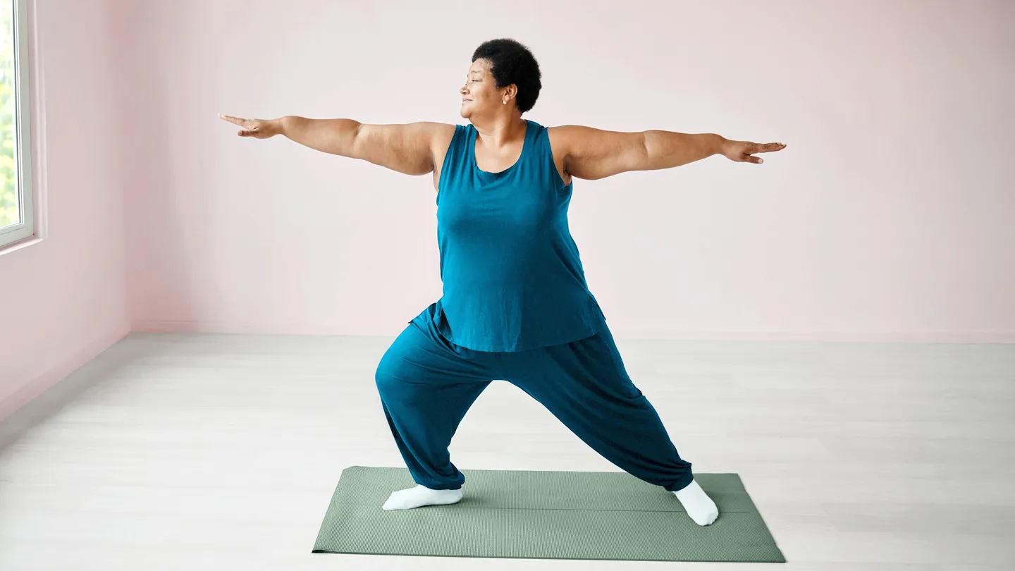 Mature woman doing yoga in her living room