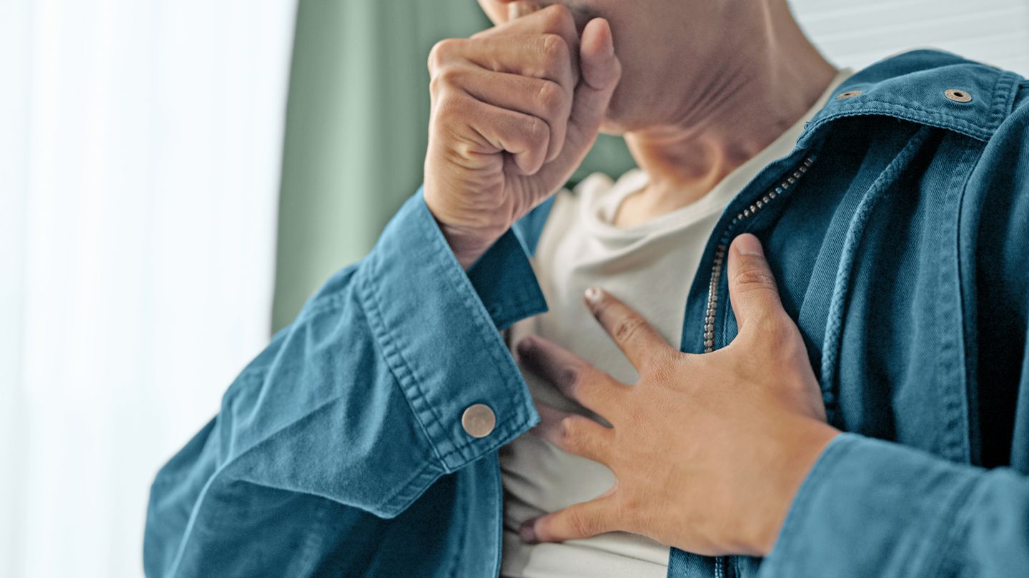 man holding his chest in pain coughing