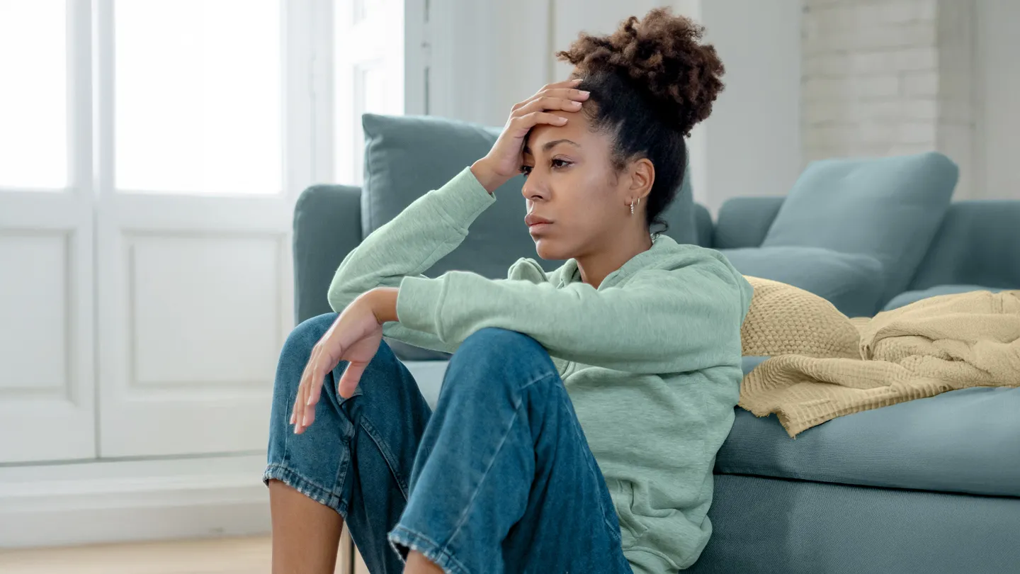 depressed woman sitting on the floor in front of her couch