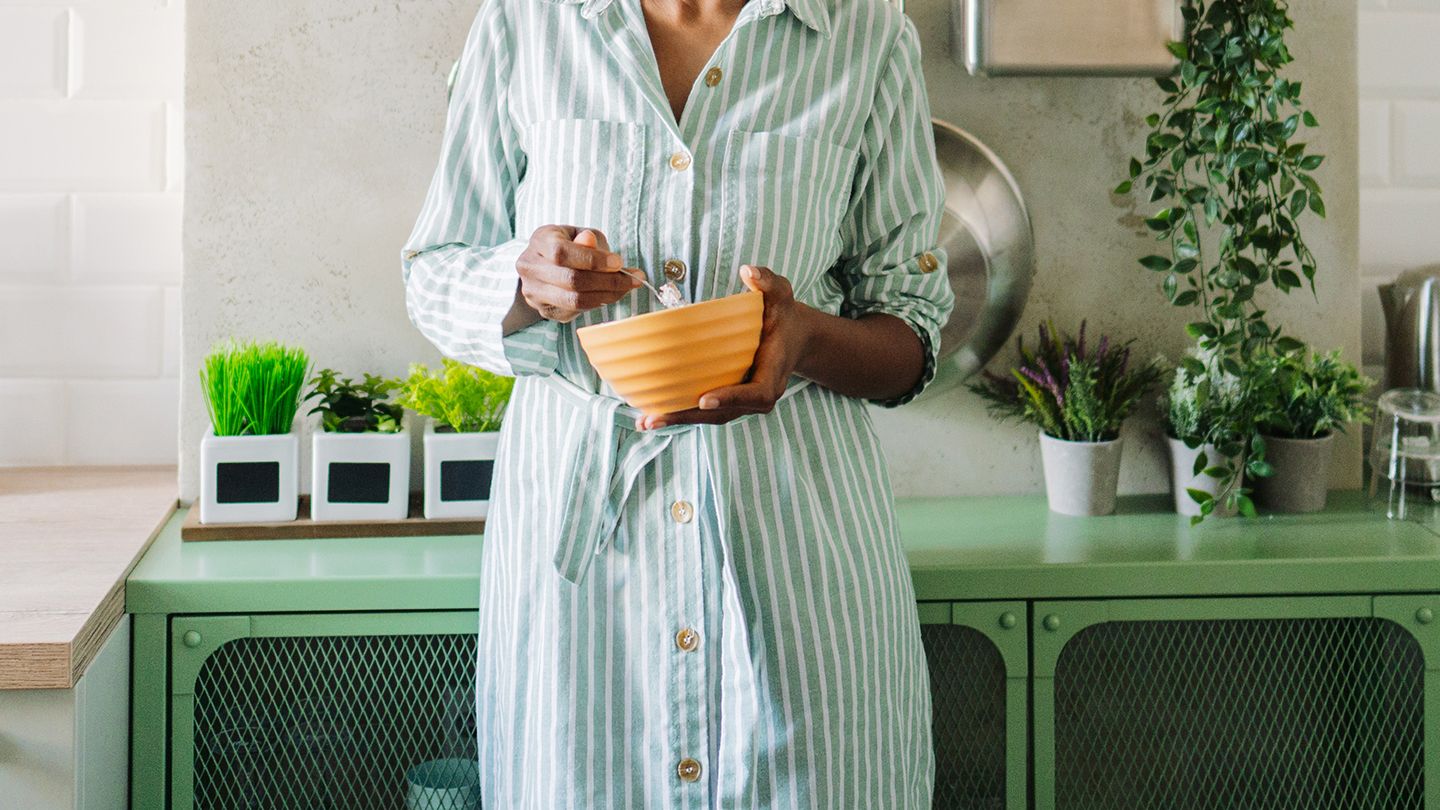 black woman eating healthy food in beautiful green kitchen