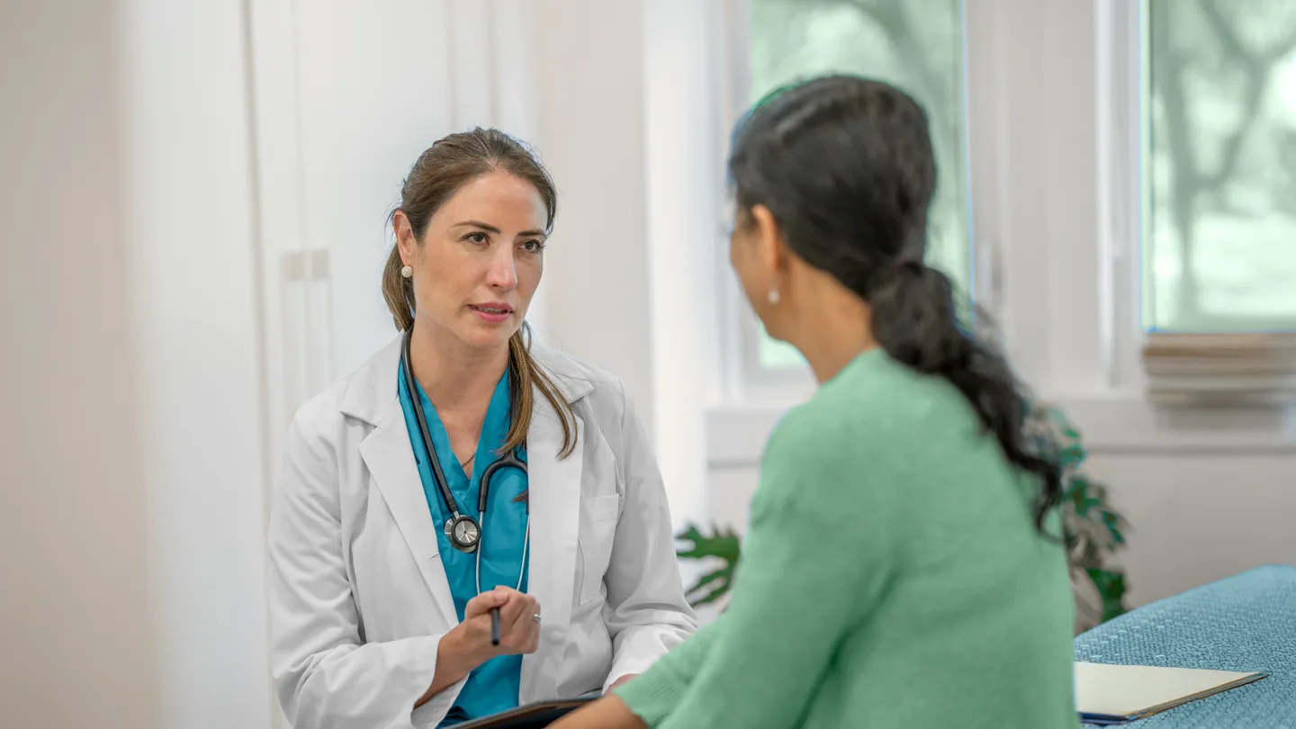 mature woman talking with her doctor in exam room