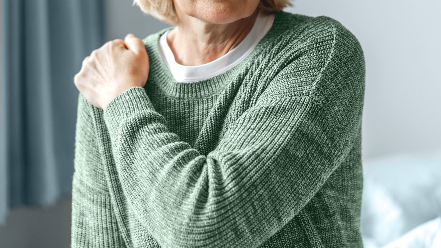 mature woman holding her shoulder in pain
