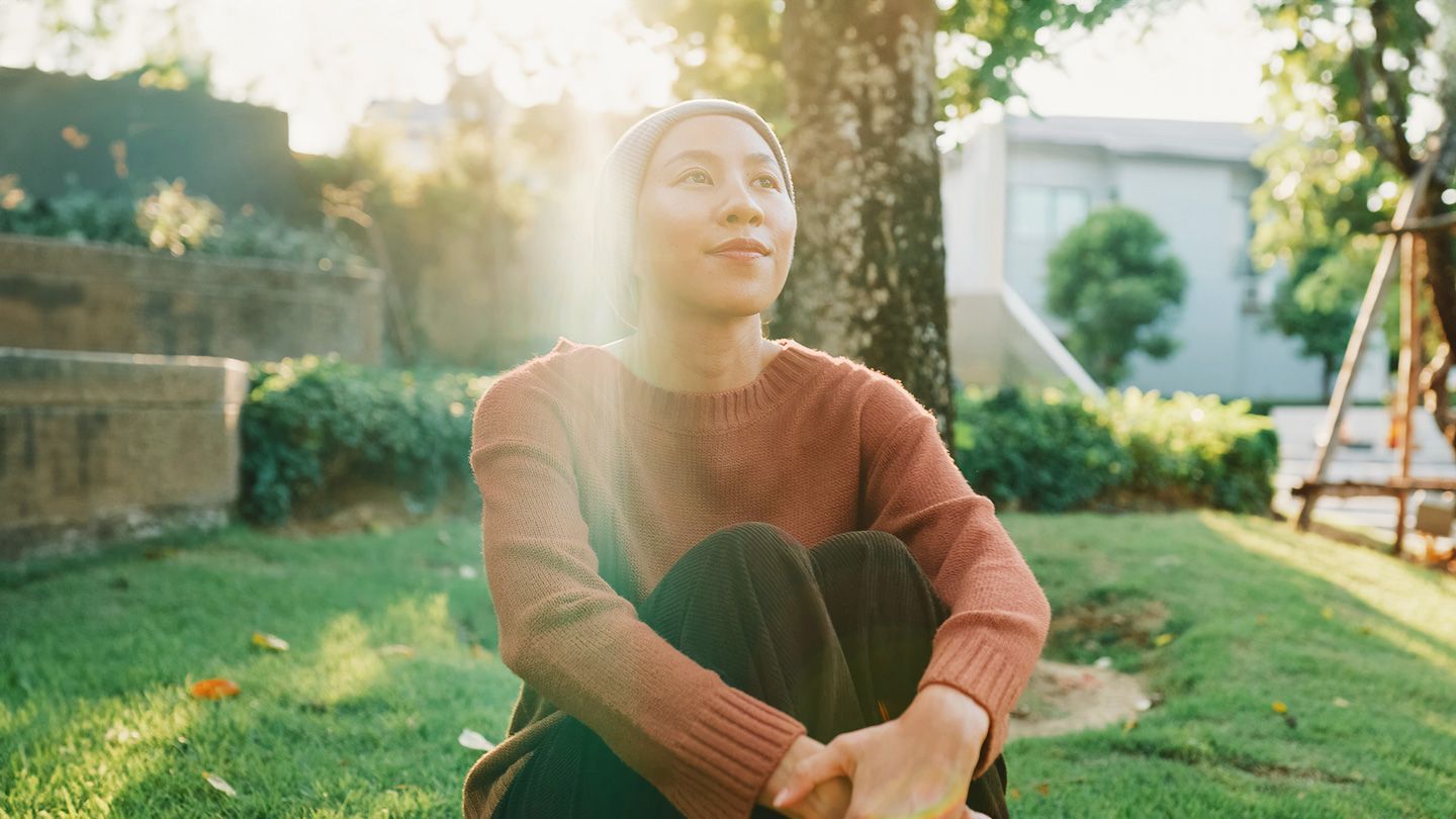 hopeful woman with headscarf on sitting outside