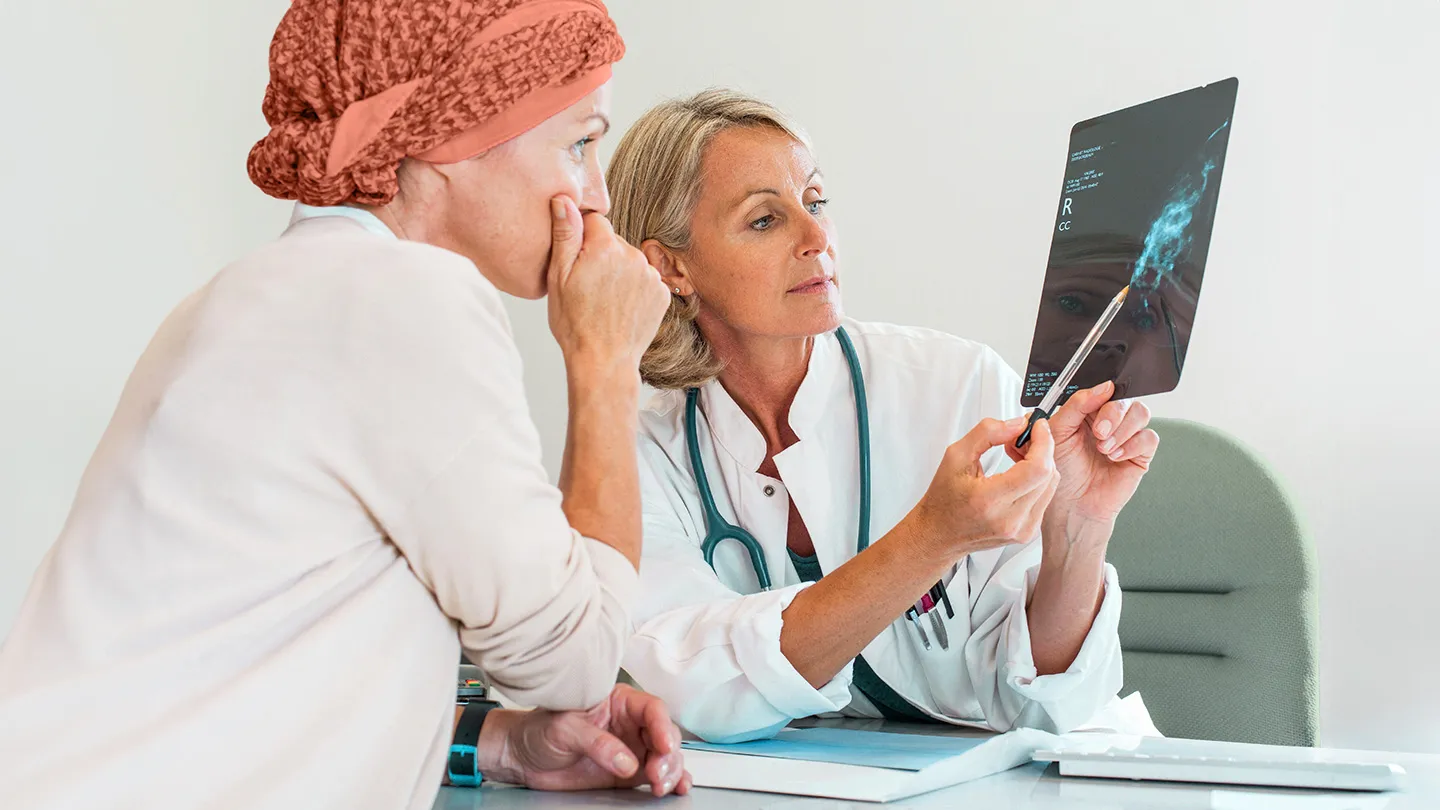 woman discussing diagnosis and treatment with doctor holding breast scan