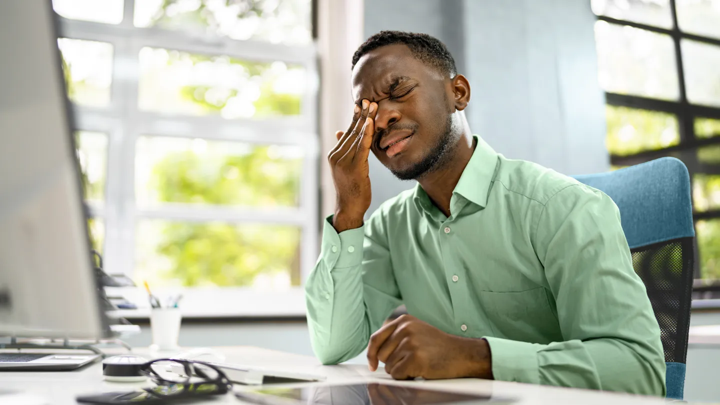 young Black man holding his right eye in agony cluster headache