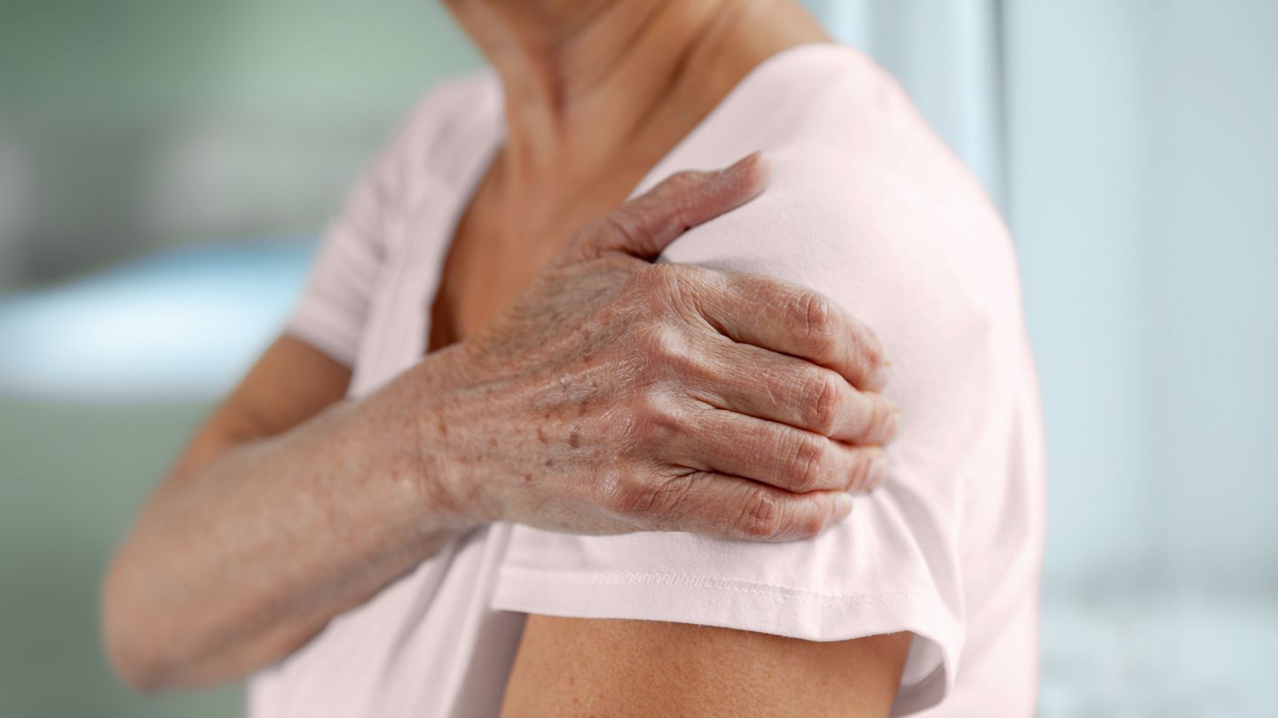 senior woman holding her left arm in pain