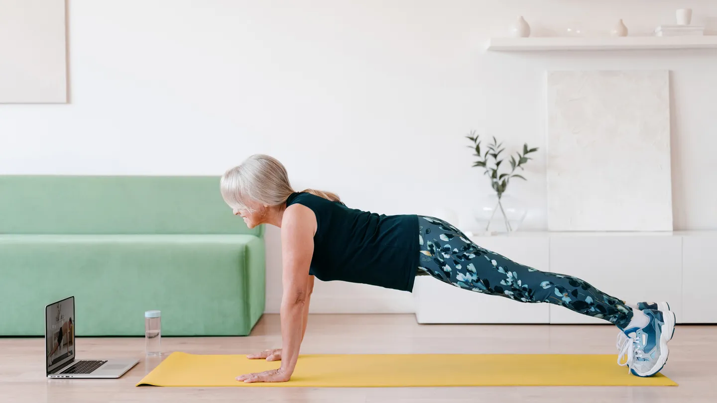 mature woman doing plank in living room