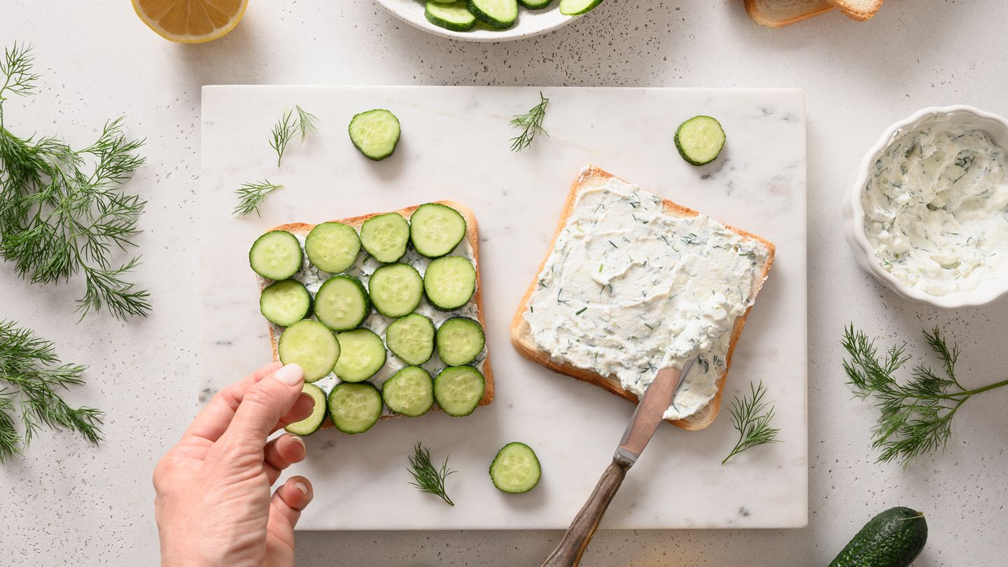 hands making cucumber sandwich