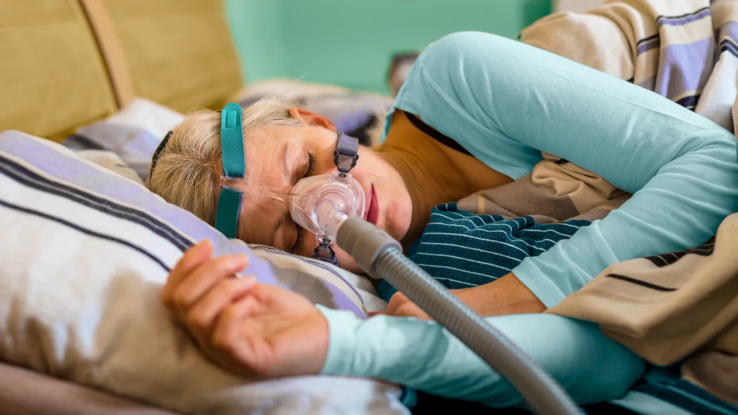 mature woman sleeping on side in long sleeves using a face sleep apnea machine device