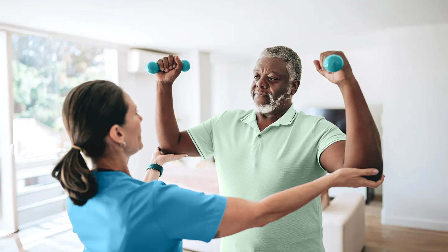 physical therapist helping mature man with RA