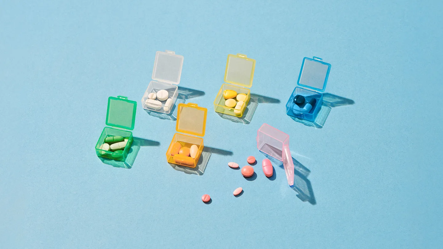 various colored individual pill boxes filled with a variety of pills and supplements medications for ulcerative colitis