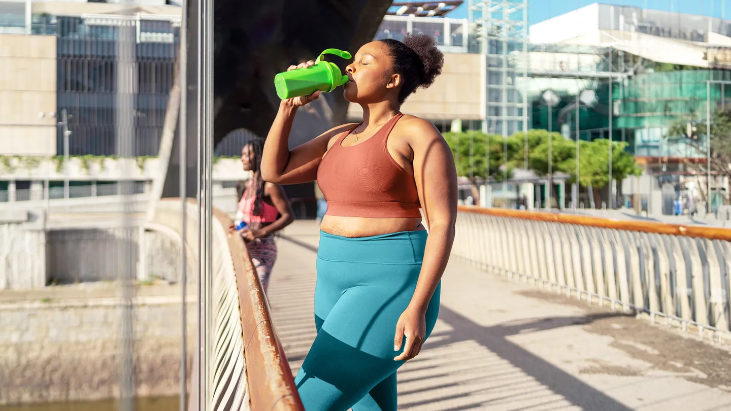 woman drinking creatine shake while working out