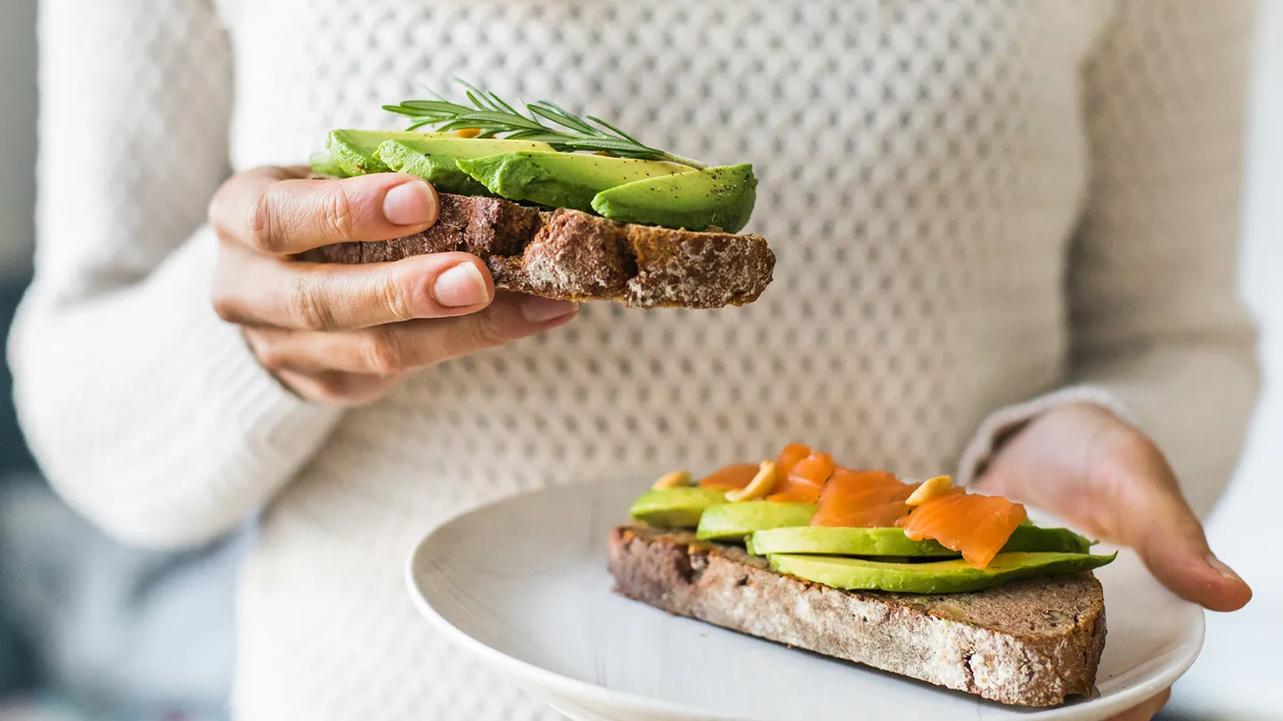 woman holding avocado smoked salmon toast