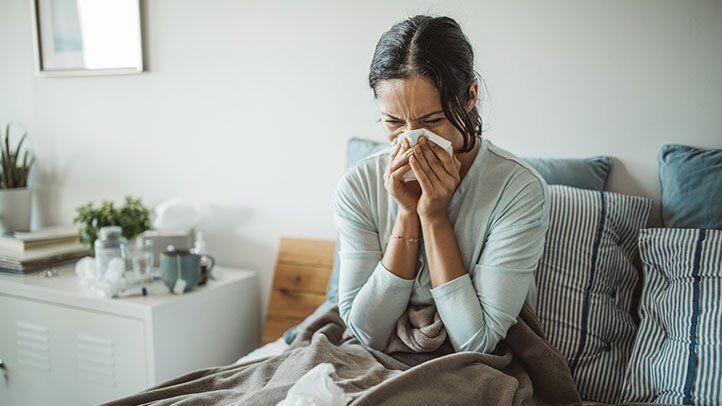 a woman with congestion blowing her nose