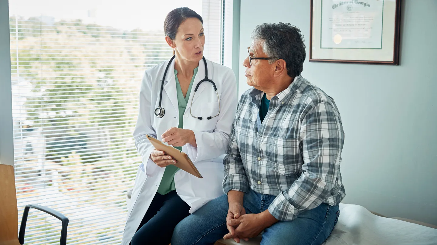 Hispanic man talking with doctor exam room
