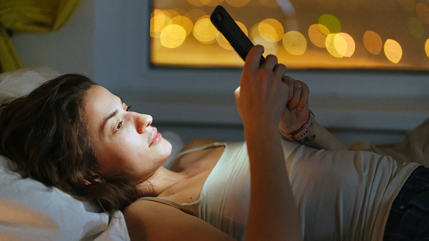 woman scrolling through phone at night