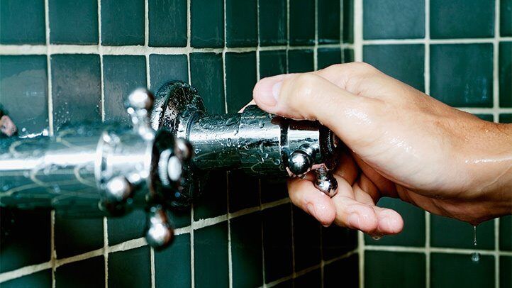 a person turning on the water in a shower