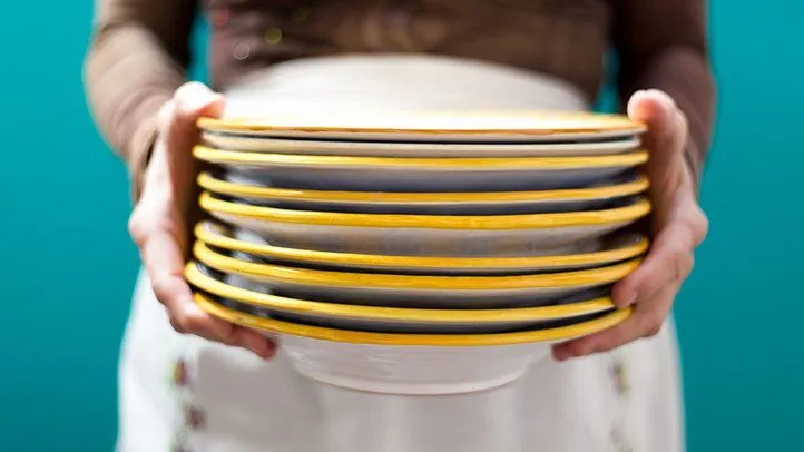 a woman holding a stack of plates