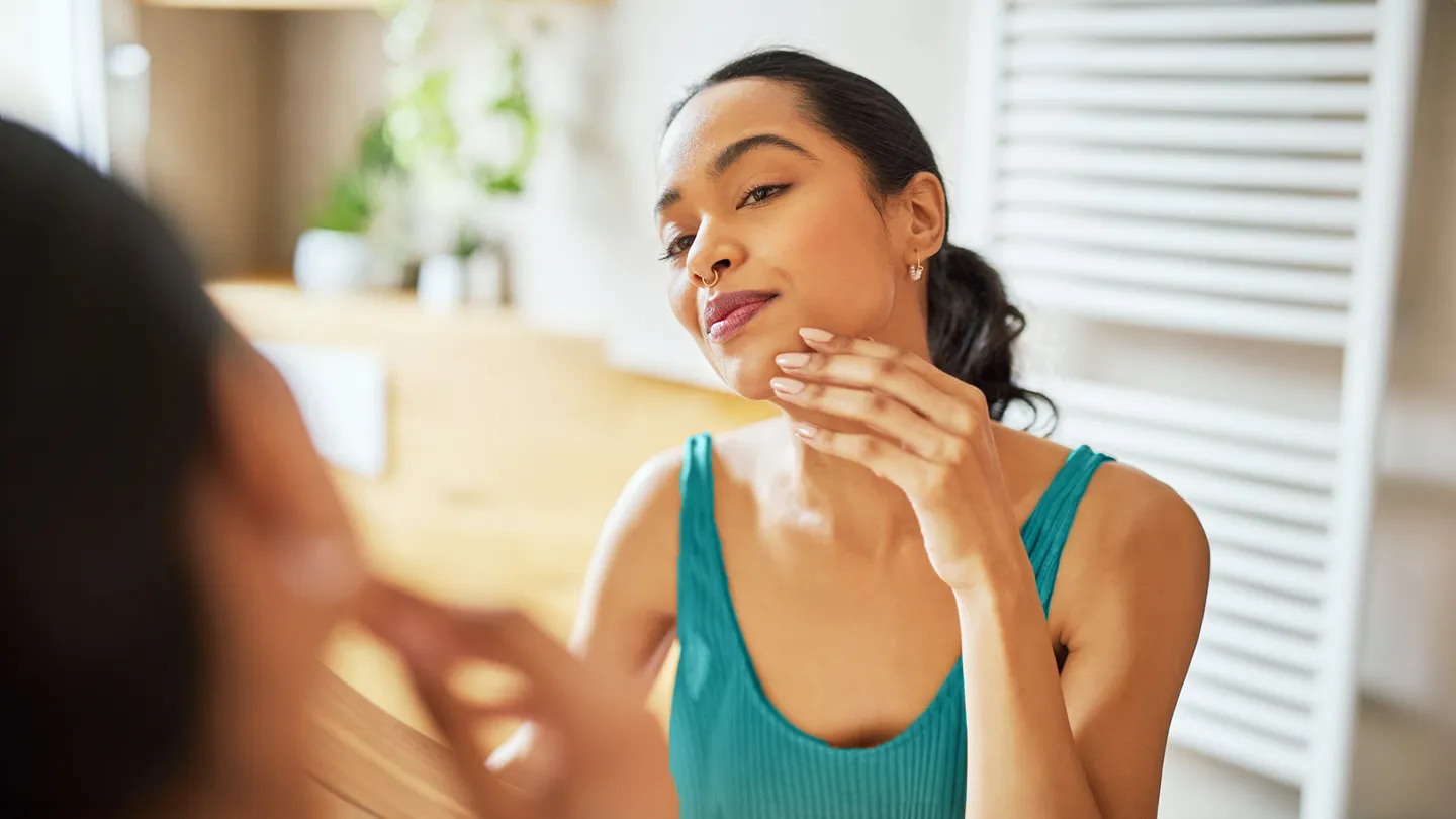in bathroom mirror woman examines skin
