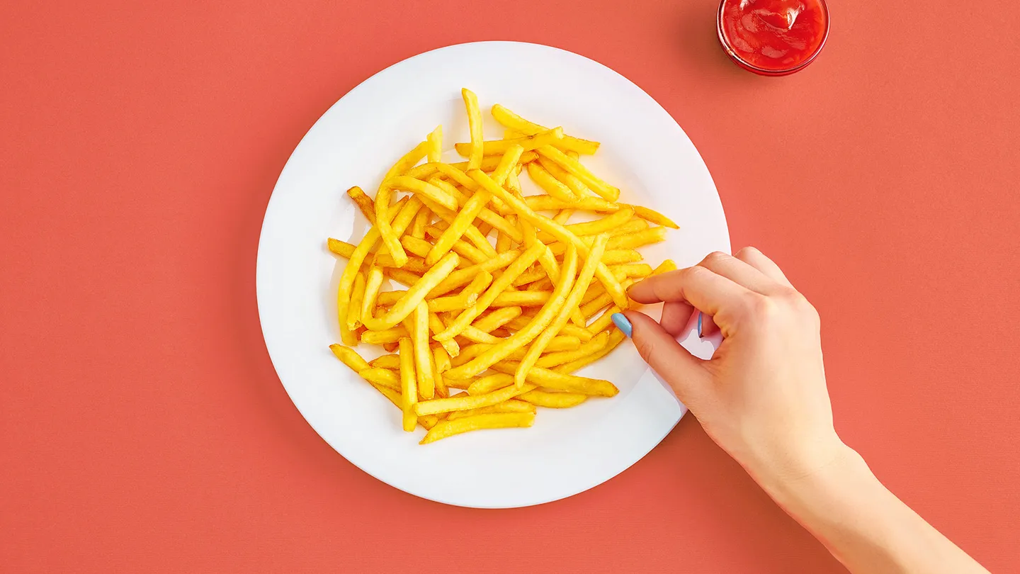 hand reaching for plate of salty high sodium fries