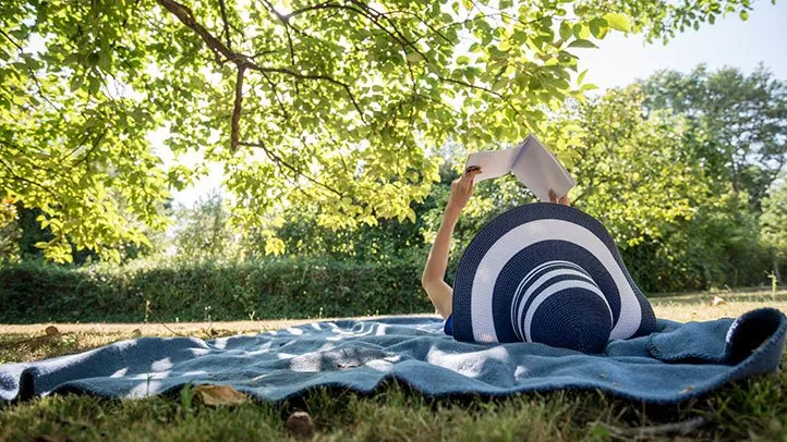 a woman reading a book outside in the sun