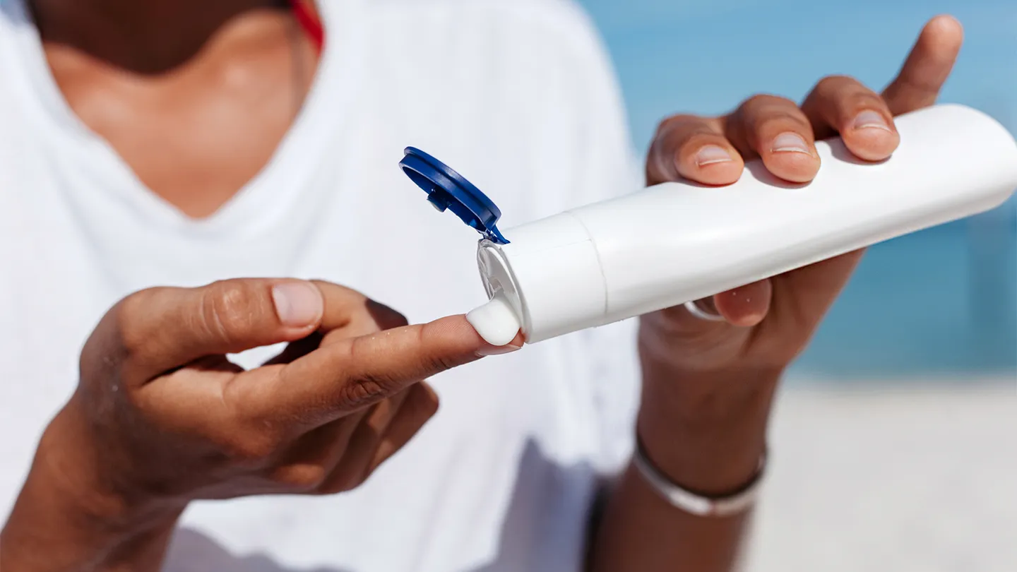 woman squeezing out sunscreen from bottle