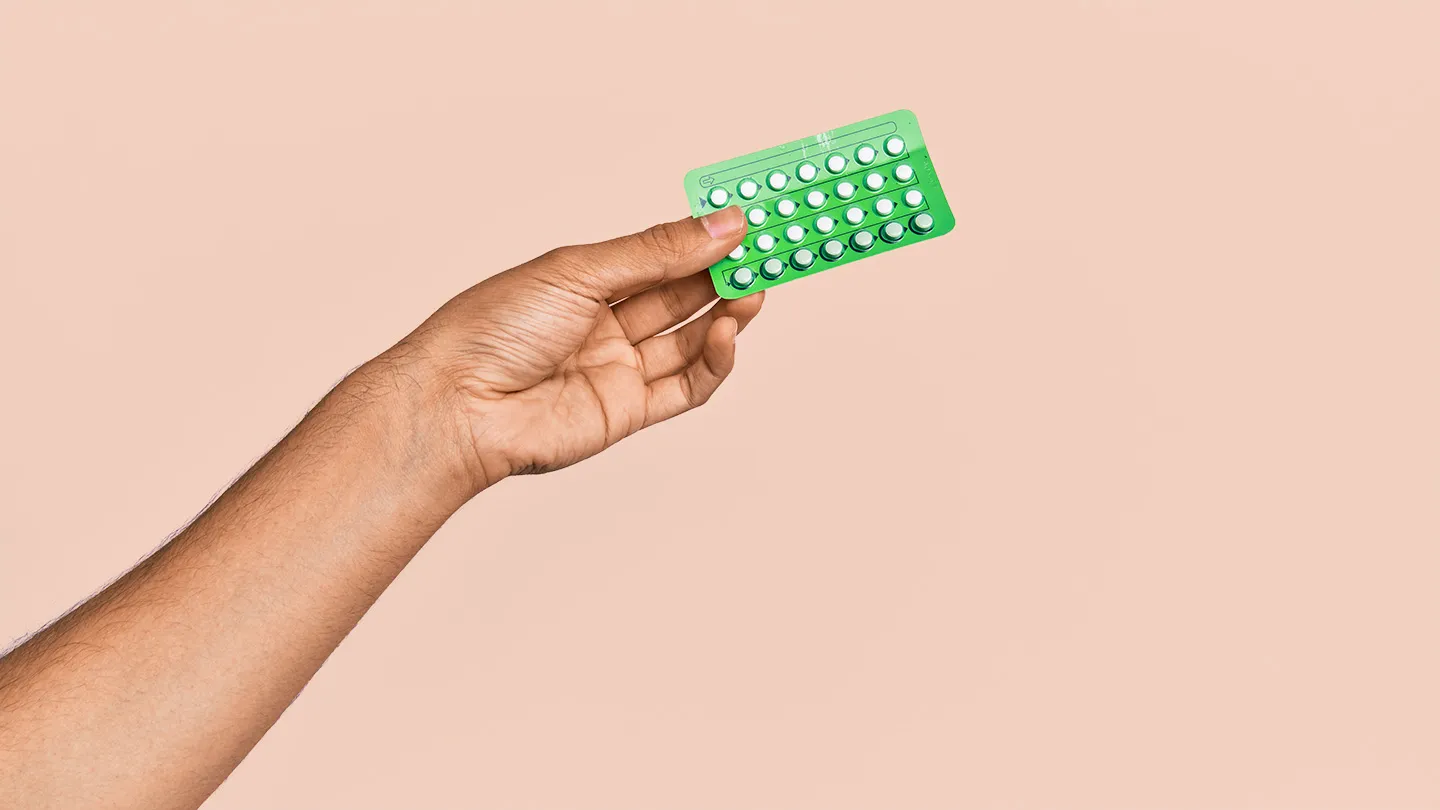 persons hand holding oral birth control pill pack