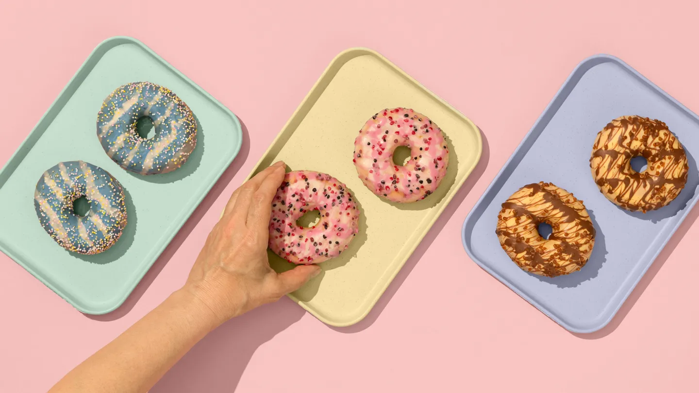 hand reaching for glazed donut on a tray