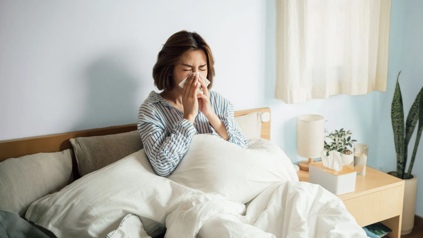 woman in bed blowing her nose