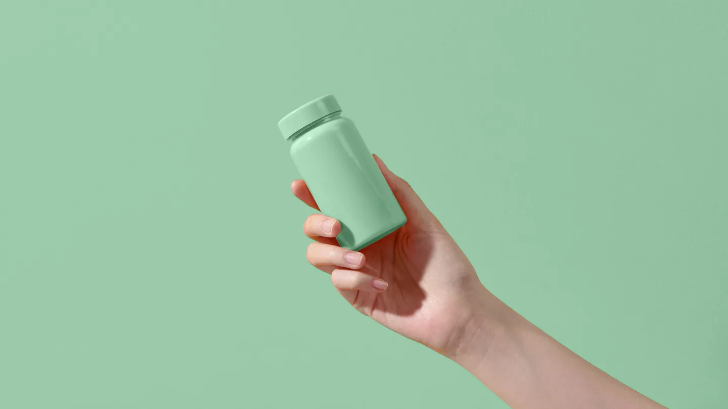 young woman's hand holding a bottle of medication