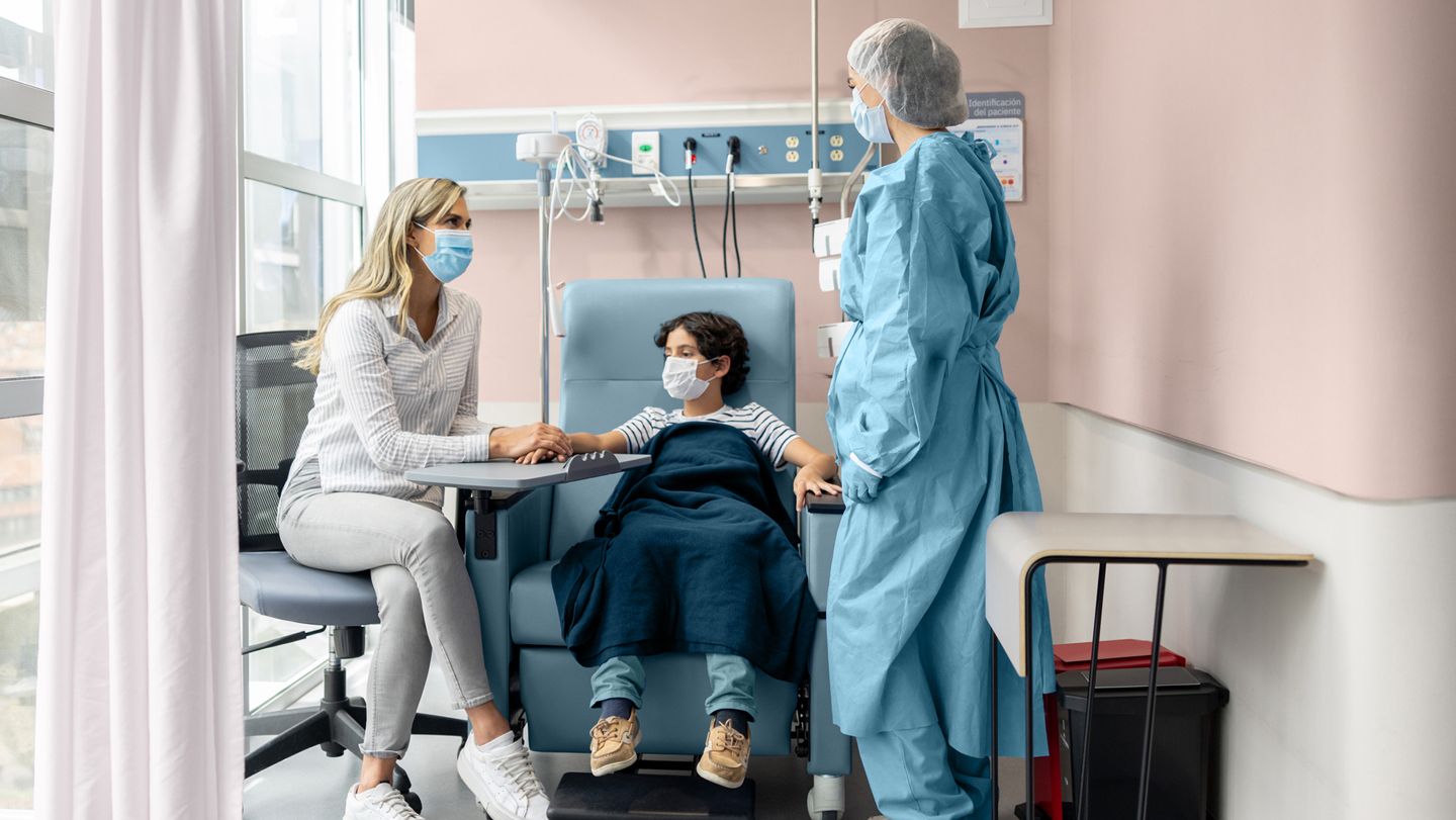 Nurse talking to the mother of a young cancer patient while getting his chemotherapy