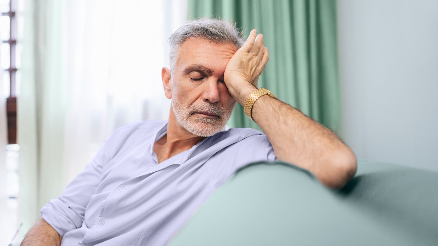 senior man exhausted sitting on couch