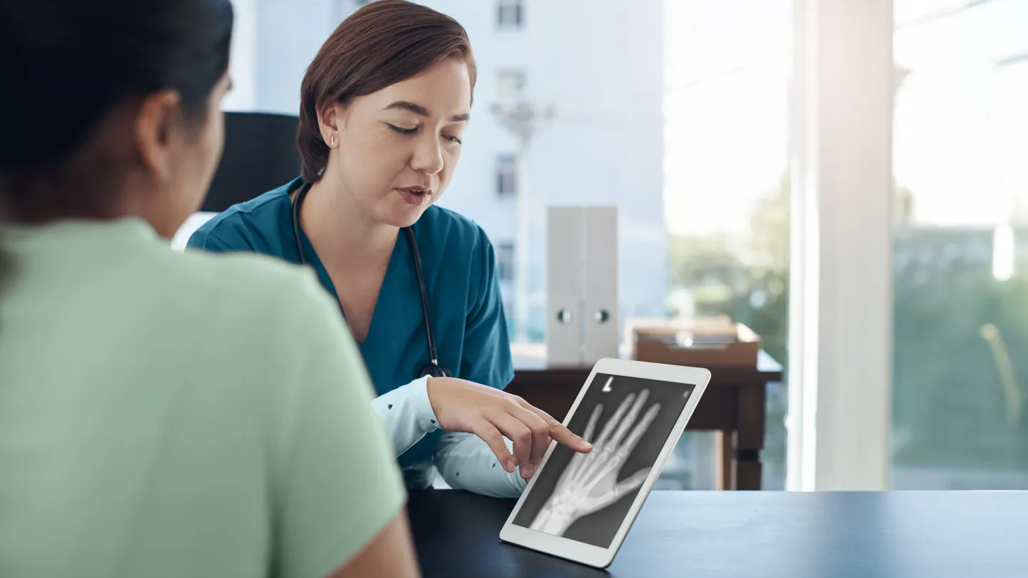 doctor discussing Rheumatoid Arthritis x-ray of patient's left hand with her