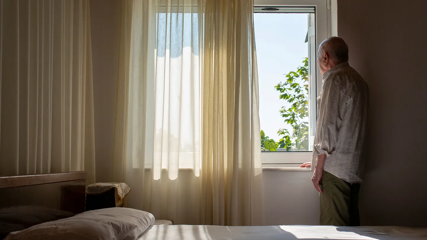 older man looking out window