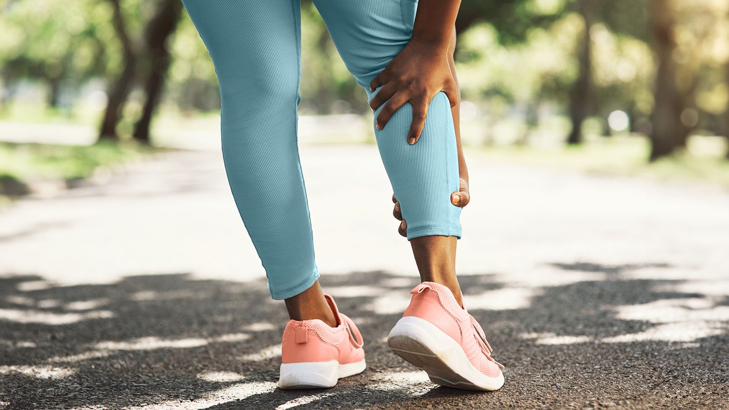 woman grabbing leg cramp outside on walk run