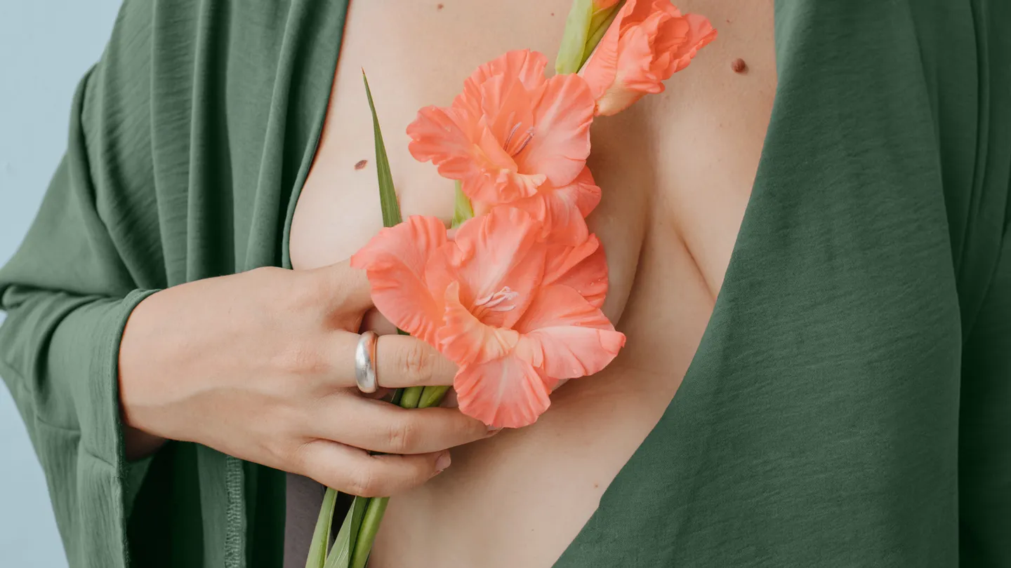 woman holding flowers to her bare breast