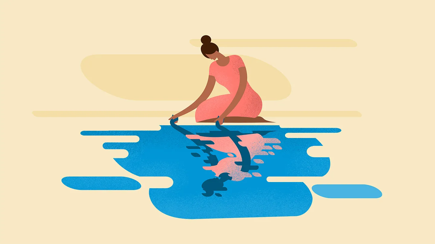 woman kneeling over blue abstract reflective puddle holding hands with distorted shadow of self in reflection