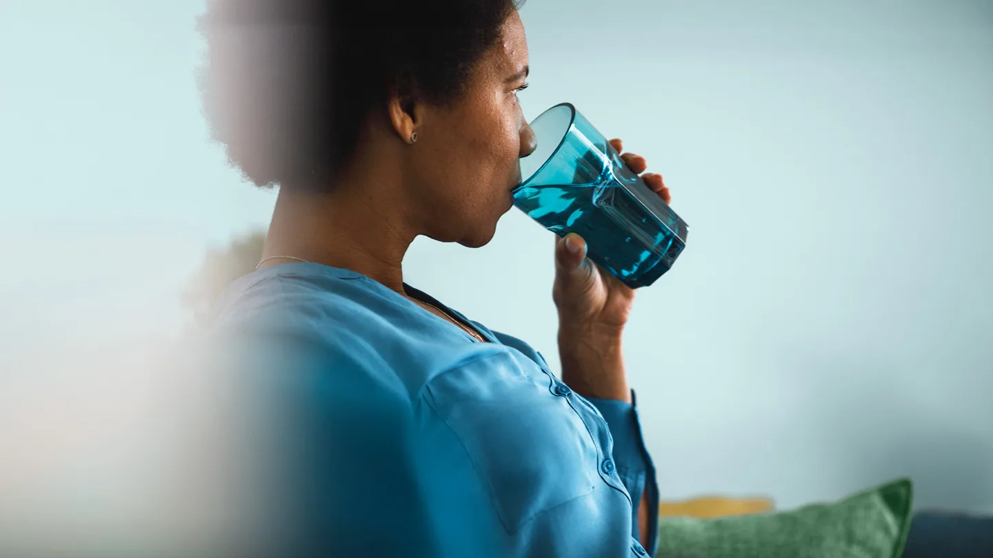 woman sitting on a couch drinking water stomach pain