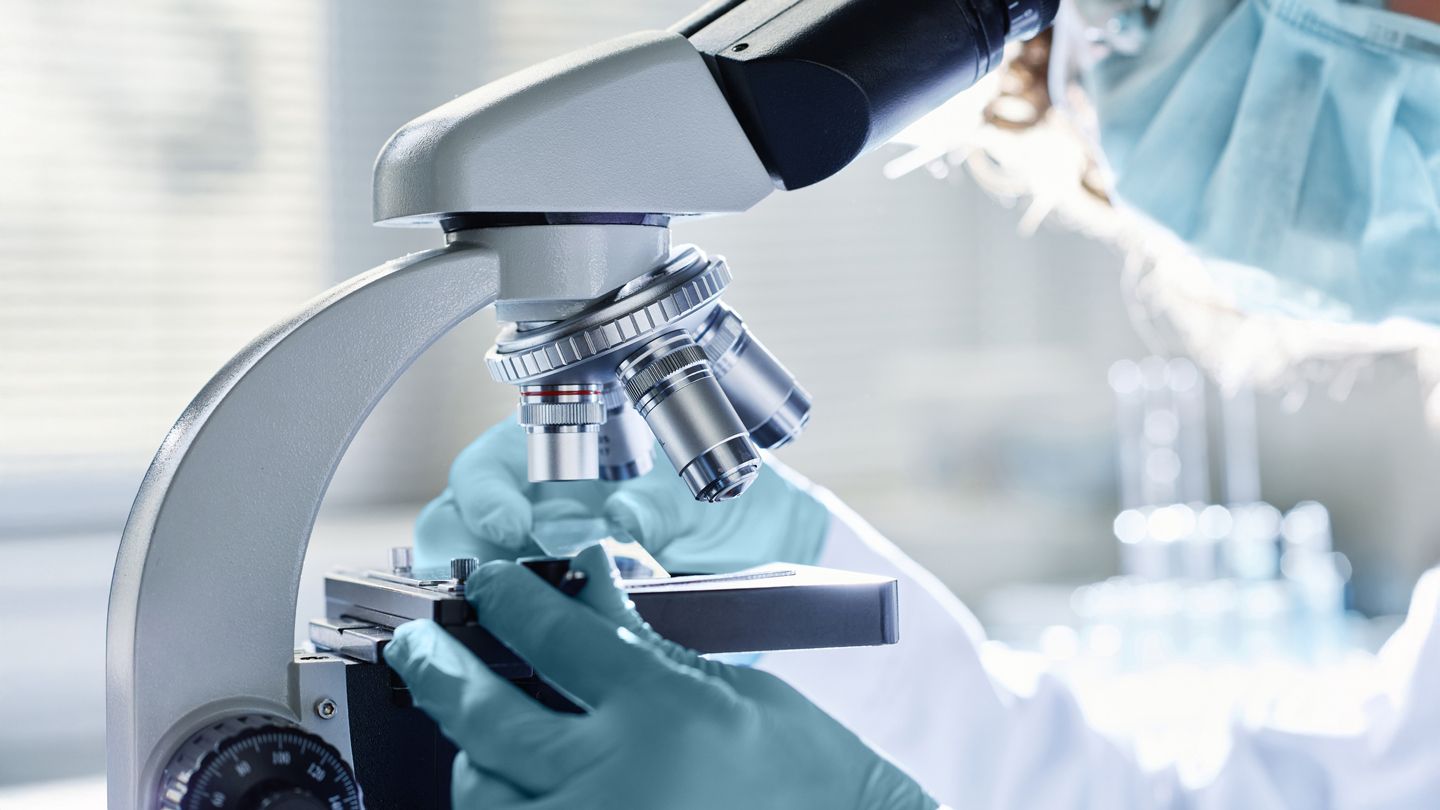 doctor looking through a microscope at a skin tissue sample