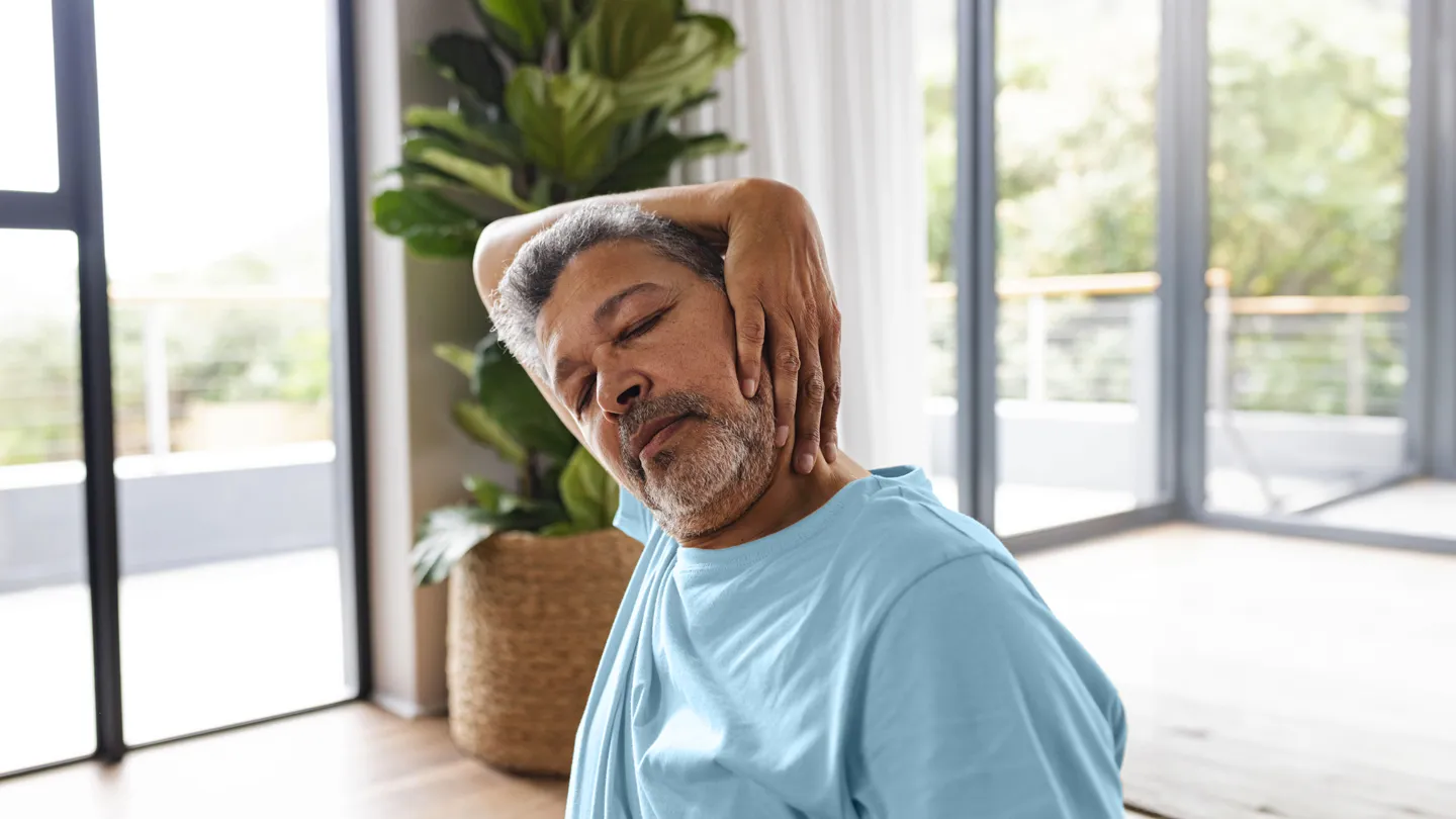 mature man with grey hair with neck pain stretching his neck with his hand