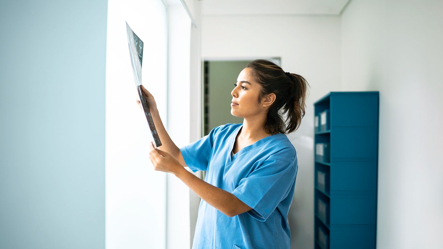 Female nurse holding up and analyzing medical x-ray of chest cavity