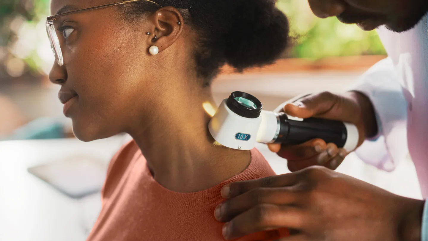 dermatologist doctor looking at black woman's skin