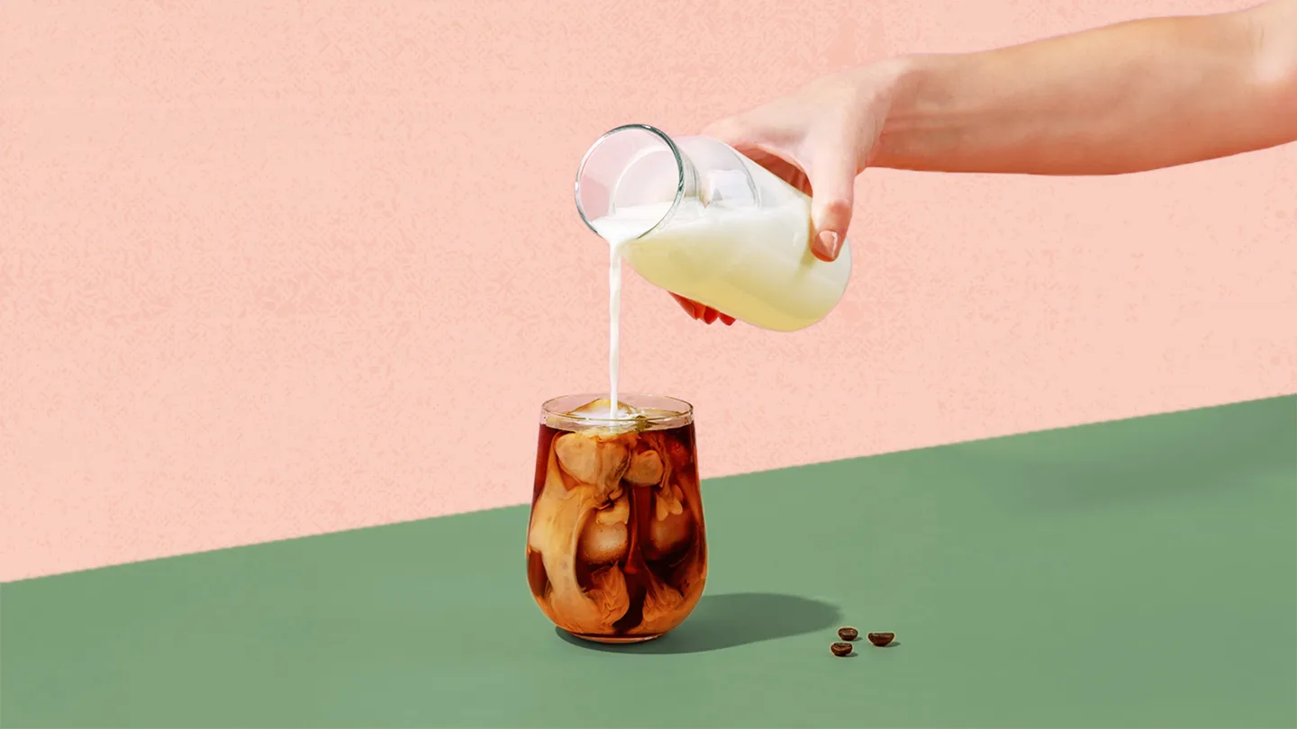 hand pouring creamer cold foam into coffee