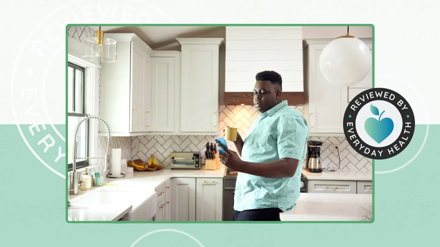Adult Black male looking at his phone in his home kitchen