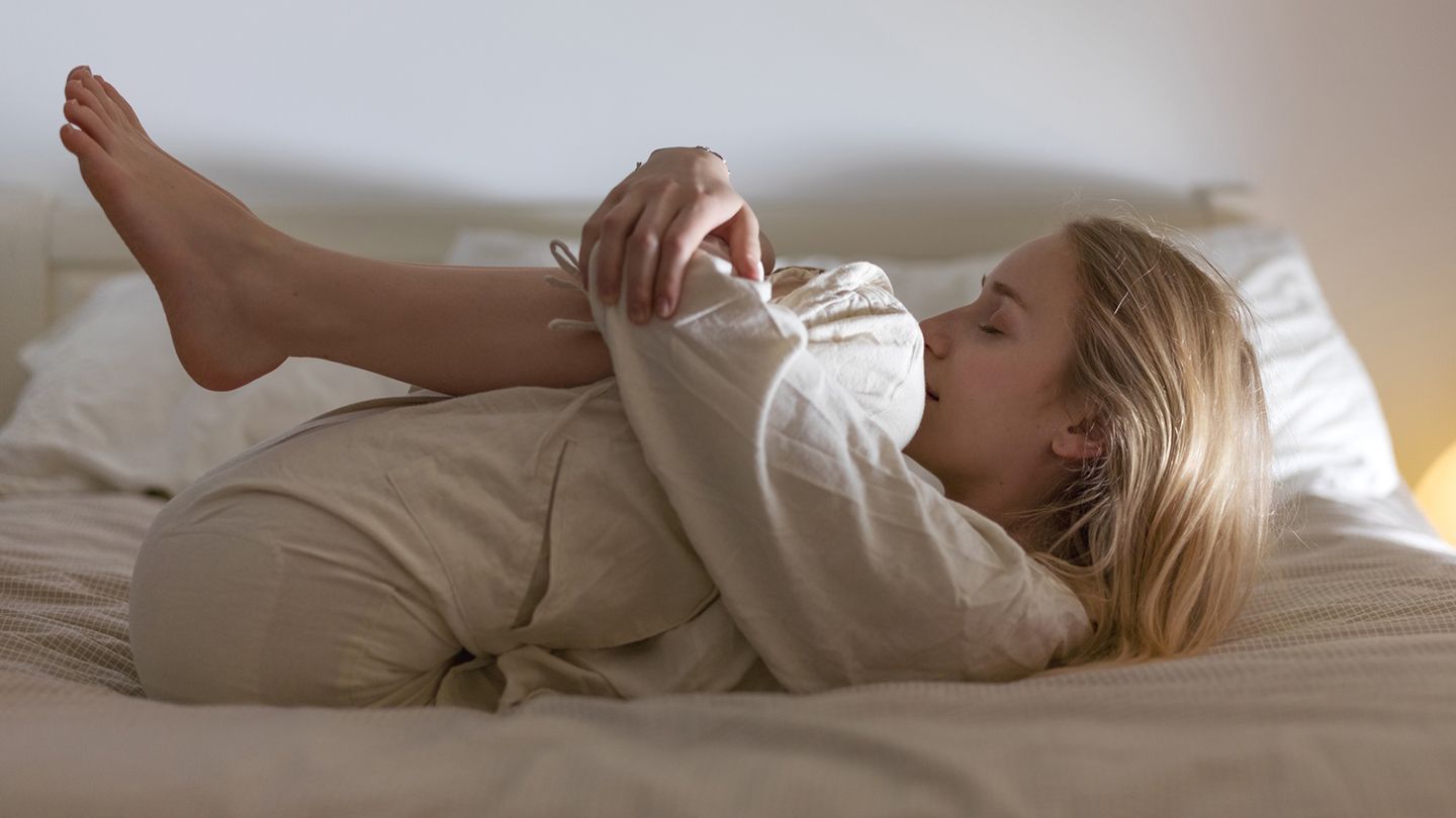 woman hugging knees in bed stretch